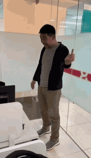 a man is standing in front of a glass wall holding a cell phone in his hand
