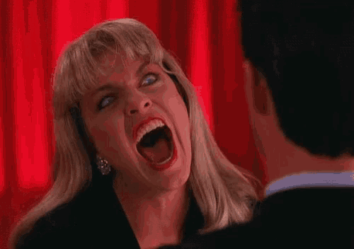 a woman is screaming in front of a man in a suit .