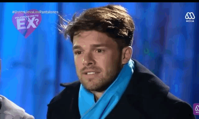 a man wearing a blue scarf and a black coat is on a tv screen with the word ex on it