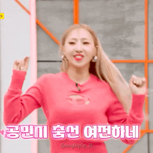 a woman in a pink sweater is dancing with her arms in the air