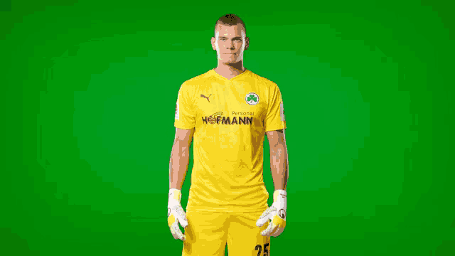 a man wearing a yellow hofmann jersey stands in front of a green screen