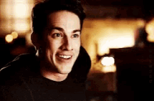 a man in a black shirt is smiling in a dark room .