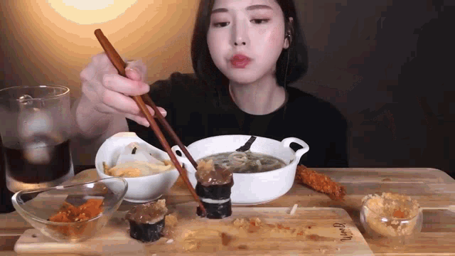 a woman is sitting at a table eating a meal with chopsticks