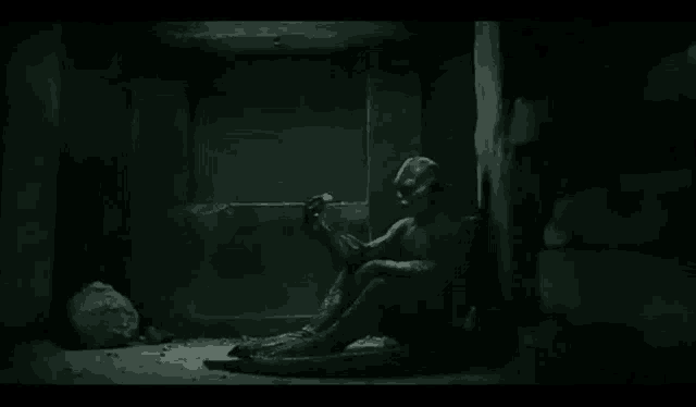 a statue of a man is sitting on the floor in a dark room .