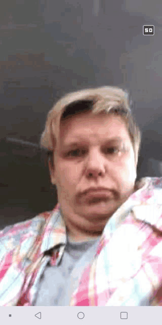 a man in a plaid shirt is taking a selfie on a cell phone
