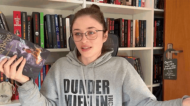 a woman wearing a grey hoodie that says dunder vienin holds a book