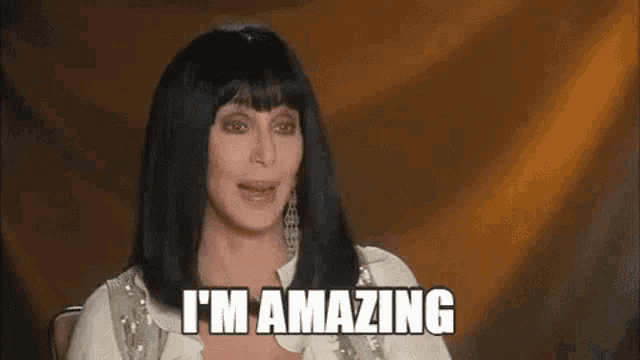cher is sitting in front of a brown background and saying `` i 'm amazing '' .