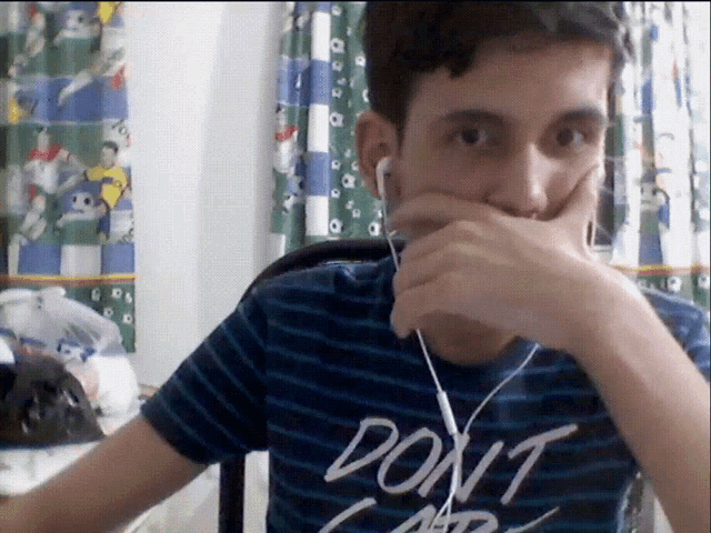 a man wearing a shirt that says do n't care covering his mouth with his hand