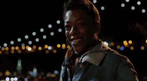 a woman in a denim jacket is smiling in front of a blurry background