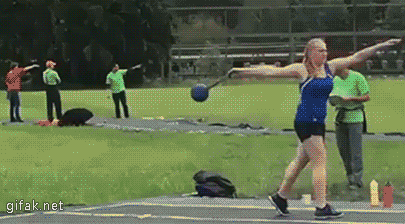 a woman is throwing a shot put ball on a track while people watch .