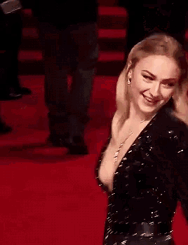 a woman is laughing on a red carpet with her mouth open