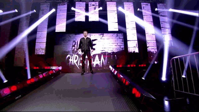 a man in a black jacket stands in front of a large screen that says christian