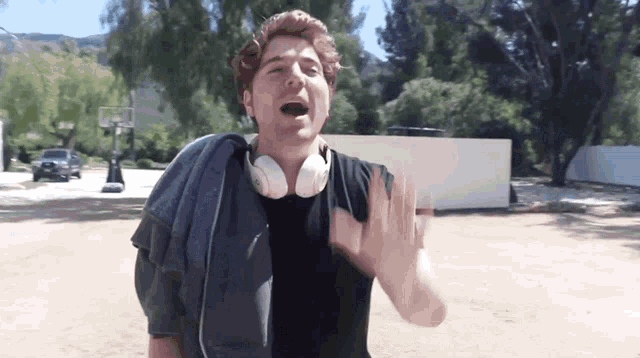 a man wearing headphones and a towel around his shoulder makes a stop sign