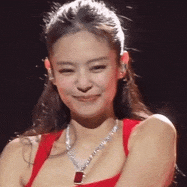 a close up of a woman wearing a red tank top and a necklace .
