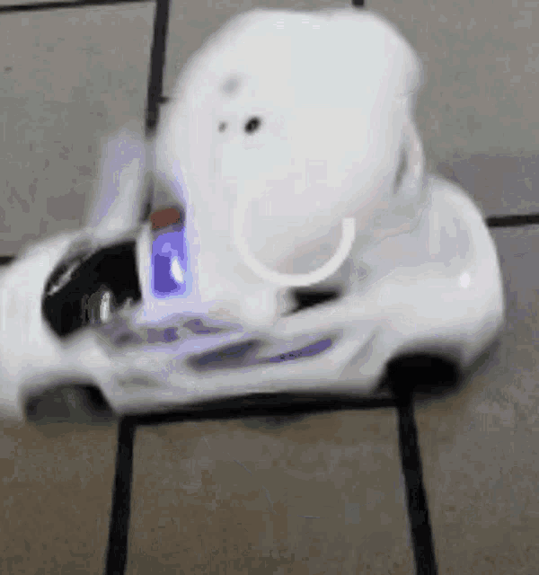 a white toy car is driving on a tiled floor with a blue light behind it