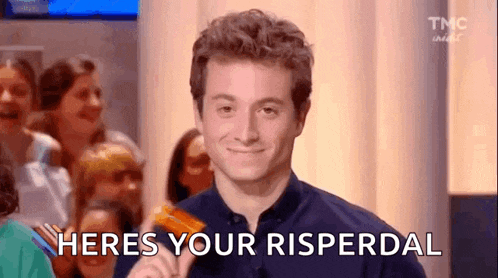 a man is holding a credit card in front of a crowd and saying `` heres your risperdal '' .