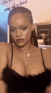 rihanna is wearing a black bra and a necklace with a cross pendant .