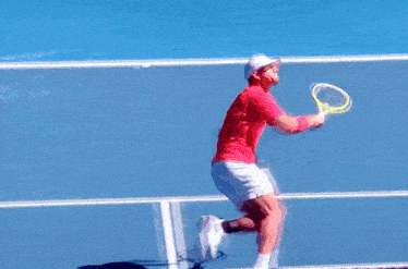 a man in a red shirt is running on a tennis court