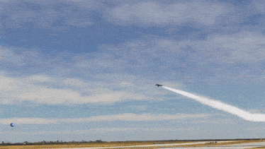 a blue and yellow jet is flying through a blue sky