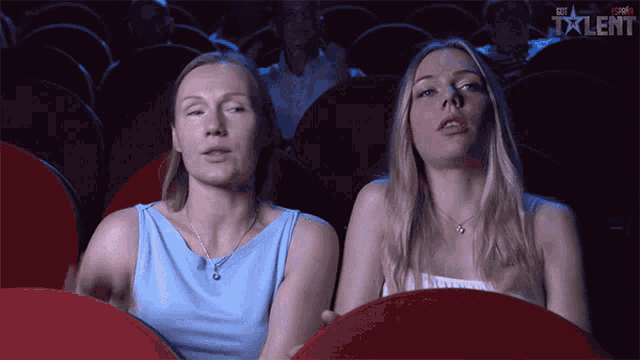 two women are sitting in a theater watching a movie and the word talent is on the screen
