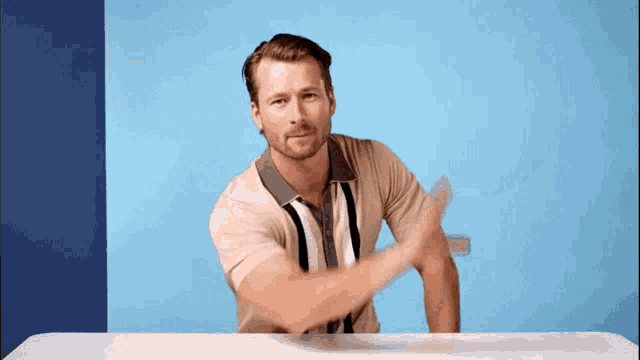 a man in a striped shirt is sitting at a table and waving his hand