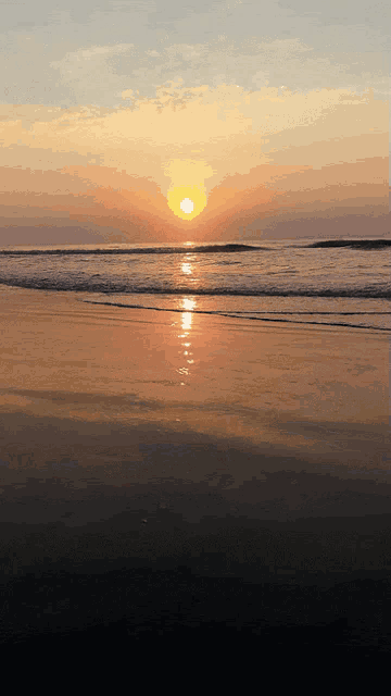 the sun is setting over the ocean and the waves are breaking on the beach