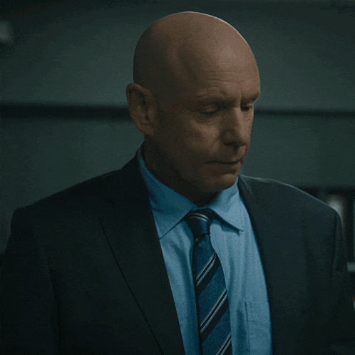a bald man in a suit and tie says f-...