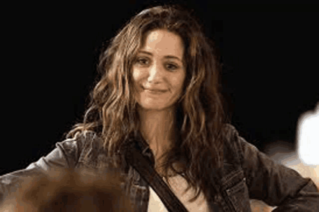 a woman with long hair is wearing a denim jacket and a white shirt .