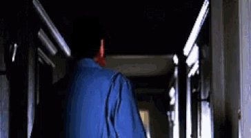a person is walking down a hallway with a blue jacket hanging from the ceiling .