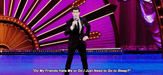a man in a suit and tie is standing on a stage holding a microphone and talking into it .
