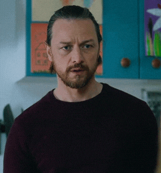 a man with a beard wearing a maroon sweater looks at the camera