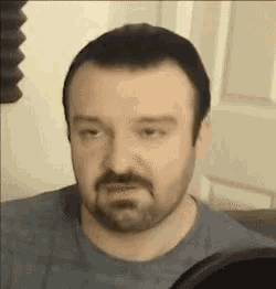 a man with a beard is sitting in front of a microphone .