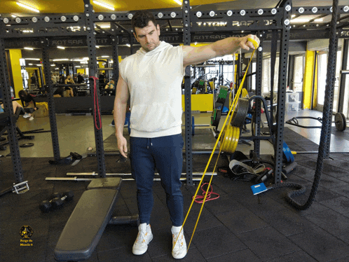 a man is holding a yellow resistance band in a gym that says titan