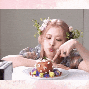 a woman with flowers in her hair is sitting at a table with a plate of food with flowers on it