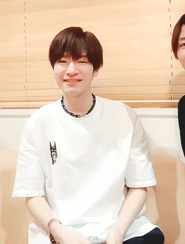 a young man wearing a white t-shirt with the letter t on the front