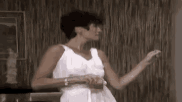 a woman in a white dress is standing in front of a wall .