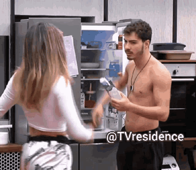 a man without a shirt is standing next to a woman in front of a refrigerator with the hashtag @tvresidence on the bottom