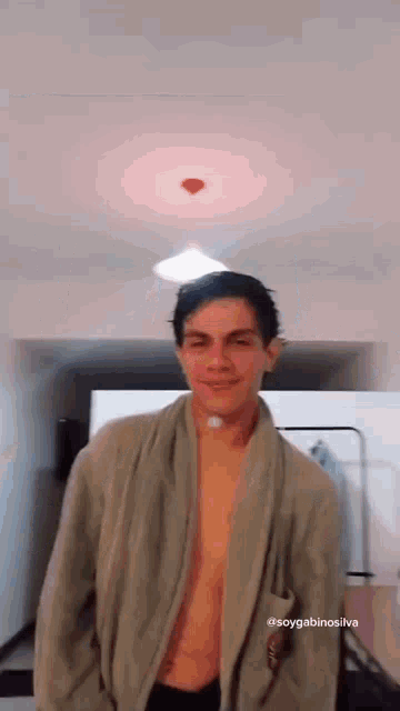 a shirtless man in a robe is standing in a room with a heart on the ceiling .