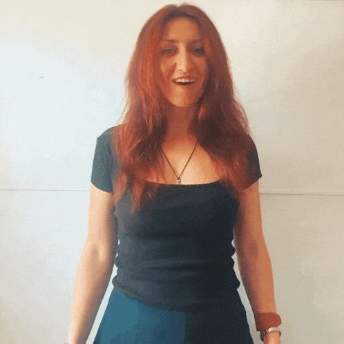 a woman with red hair is wearing a black shirt and blue pants