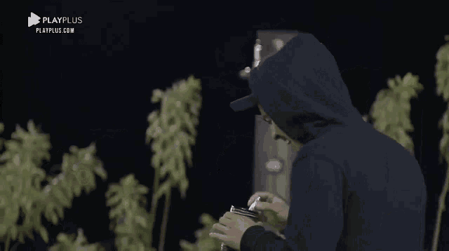 a man wearing a hoodie and a hat is holding a container .