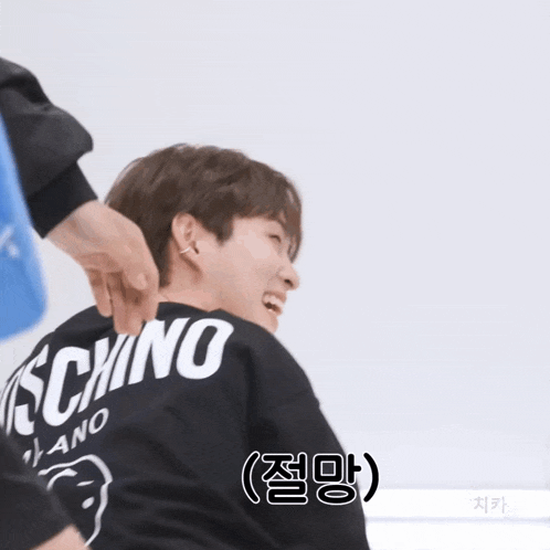 a man wearing a black moschino shirt is laughing
