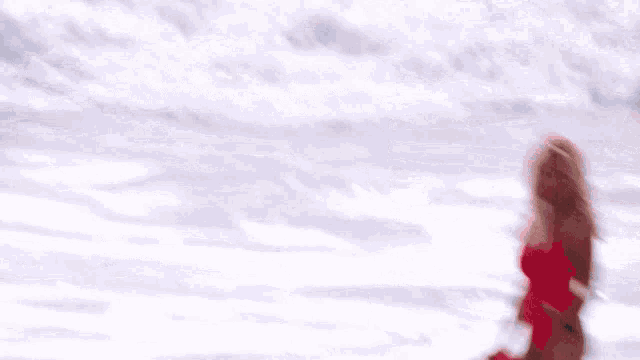 a woman in a red bathing suit is holding a life preserver in the ocean