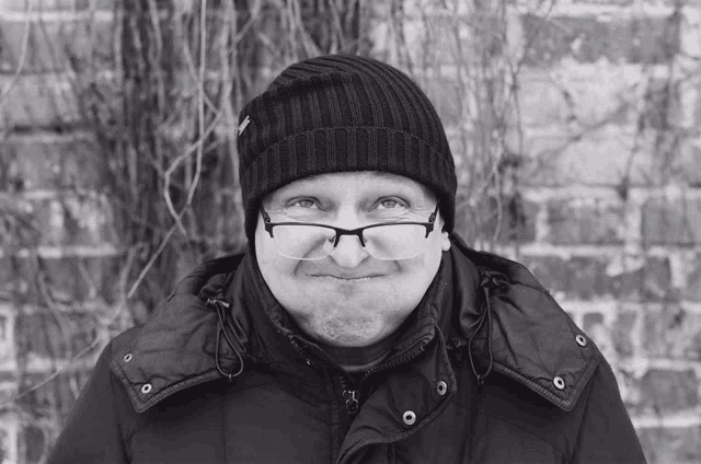 a black and white photo of a man wearing glasses and a black jacket