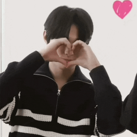 a man making a heart shape with his hands in front of his face