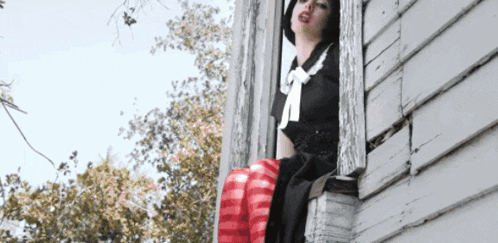 a woman in a black dress is looking out of a window .