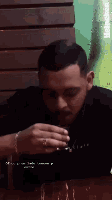 a man sitting at a table drinking a heineken beer