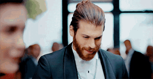 a man with a beard is wearing a tuxedo and smiling