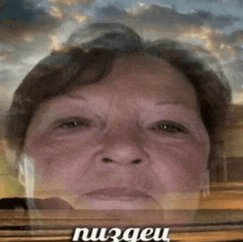 a close up of an older woman 's face with a cloudy sky in the background