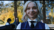 a young woman in a school uniform and tie is smiling .
