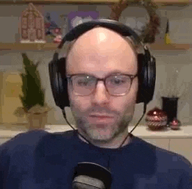a bald man with glasses is wearing headphones and a microphone .